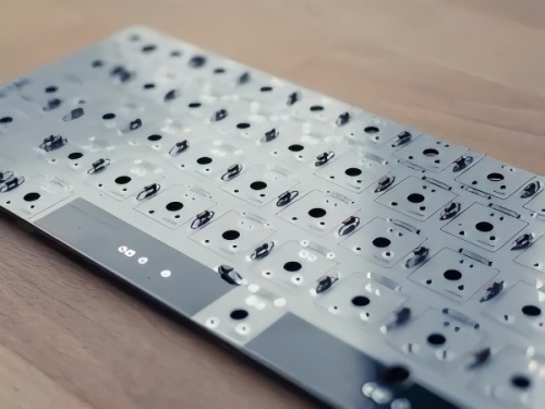 Bare keyboard PCB with metal substrate design, featuring key switch pads and positioning holes for connecting mechanical keyboard switches