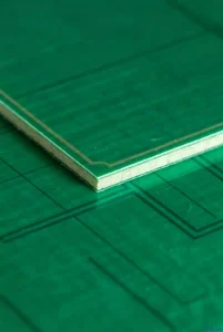 A macro photograph of FR4 material, a typical green PCB substrate material, featuring a smooth green solder mask layer and visible glass fiber texture on its surface.