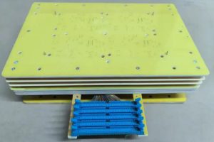 Multi-layer PCB ICT test fixture with yellow epoxy fixture plate, blue test pin connectors and wiring harness for circuit board electrical testing.